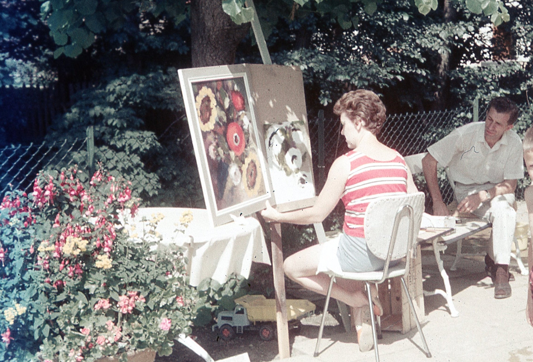 My Omi sitting at her easel, painting flowers in her backyard.